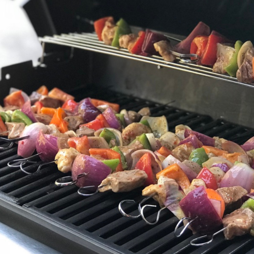 Beef and chicken kabobs grilling over open flames, loaded with colorful bell peppers and onions, perfect for a summer cookout.
